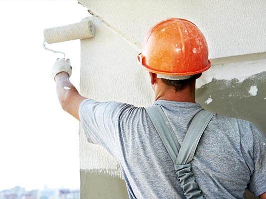 Imagen utilizada para el servicio de pintura de naves y fachadas donde se observa como un pintor realiza dicho trabajo